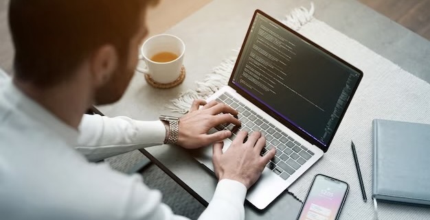 A man writes program code on a computer while sitting at a table