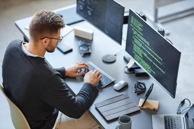 A man sits at a computer and programs
